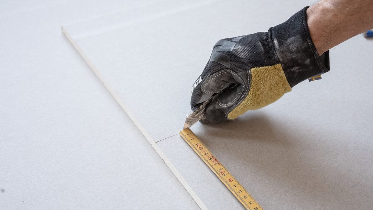 A gloved hand using a ruler for precise measurements in a construction project.